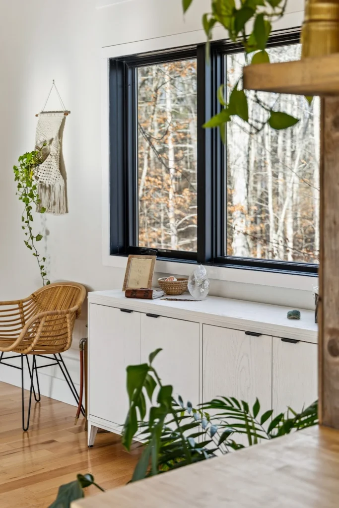 Bright room with white walls, large window overlooking a forest, and a light wood cabinet